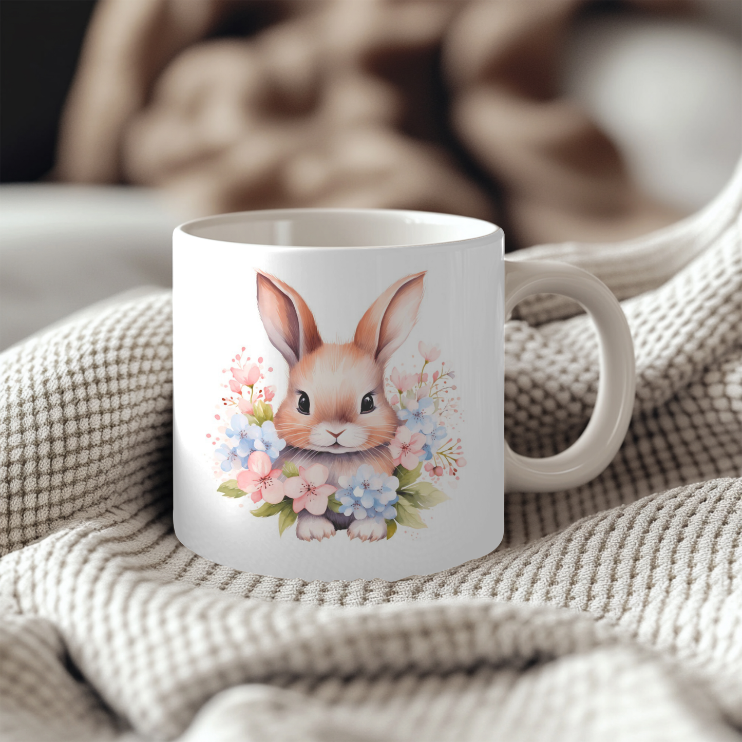 A white ceramic mug with a floral design featuring a cute bunny rabbit surrounded by colorful flowers.