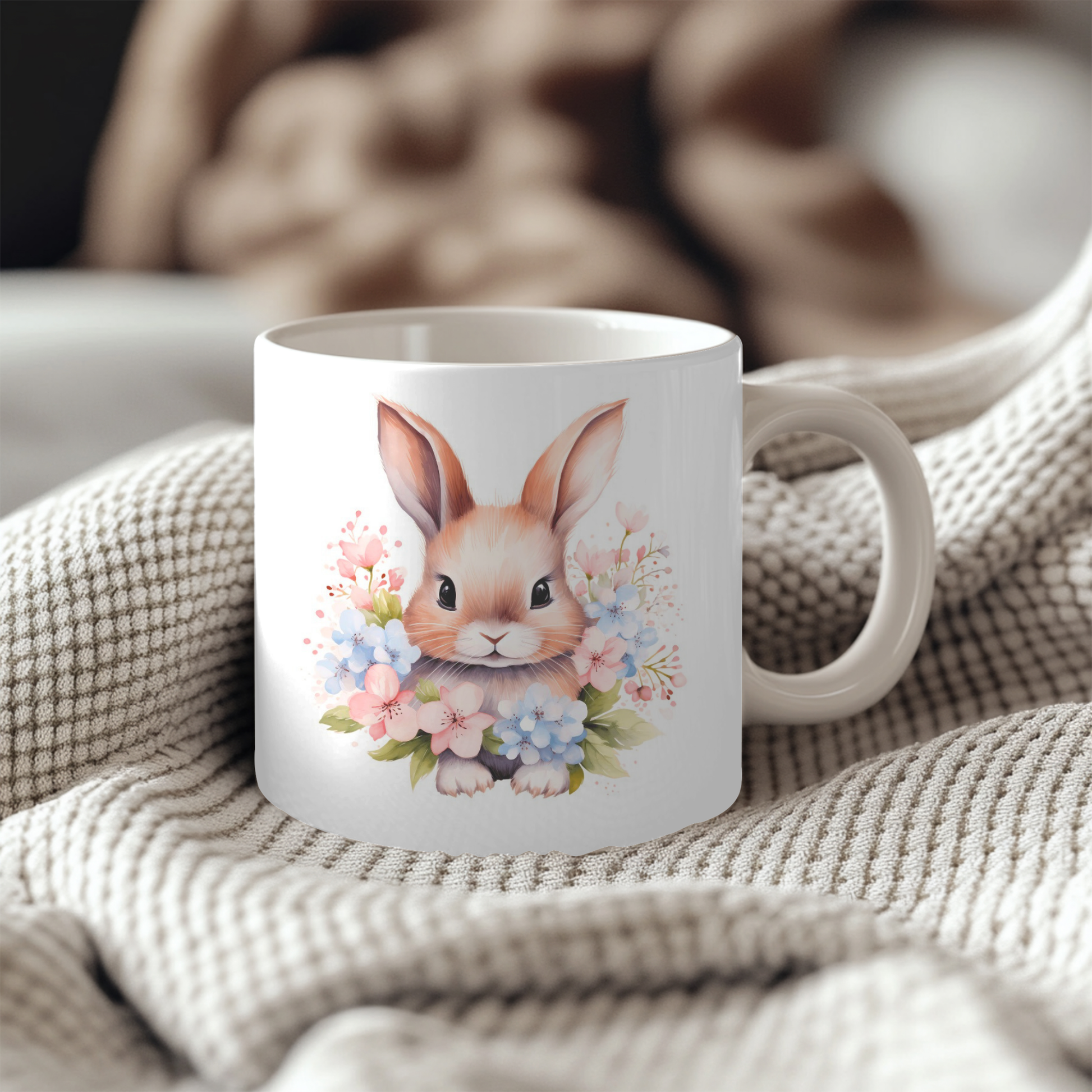A white ceramic mug with a floral design featuring a cute bunny rabbit surrounded by colorful flowers.