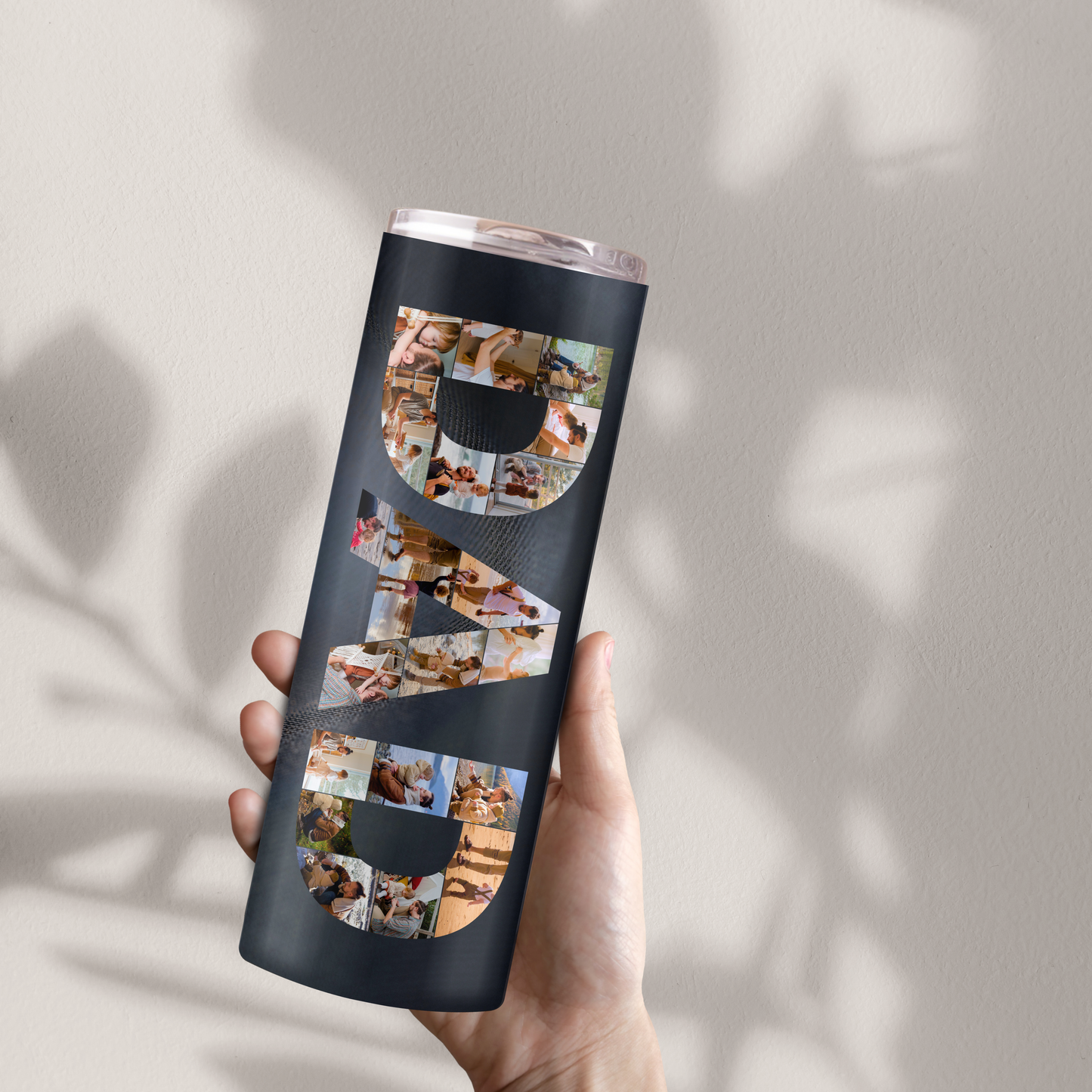 A person's hand holding a black tumbler with the word "DAD" printed on it in large letters.