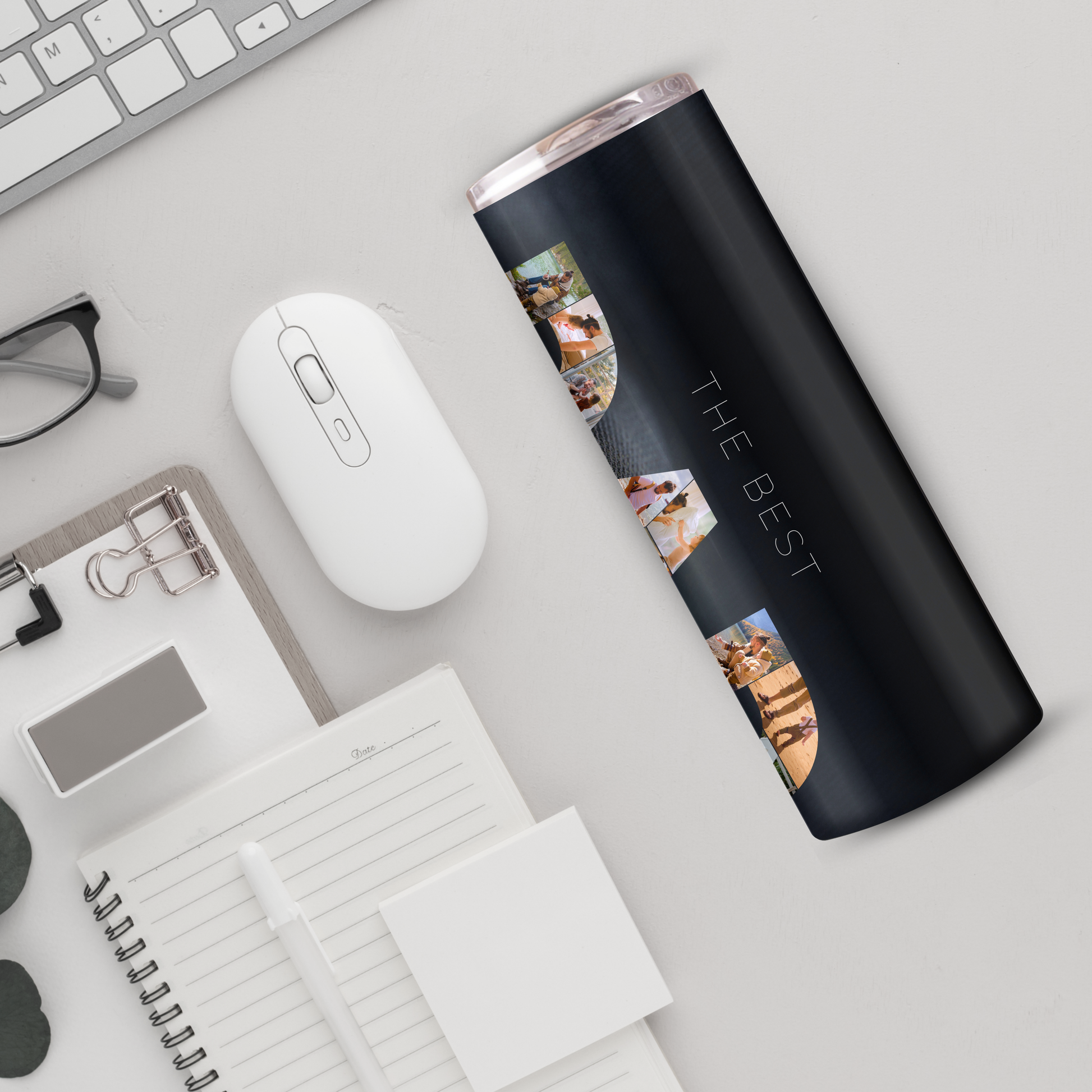 a variety of office supplies and accessories, including a computer mouse, a notebook, a pen, a pair of glasses, and a black tumbler with the text "THE BEST" printed on it.