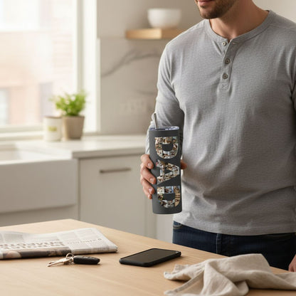 A man is standing in a kitchen holding a black tumbler with the word "DAD" printed on it. The kitchen counter has various items such as a newspaper, a cell phone, and a set of keys.